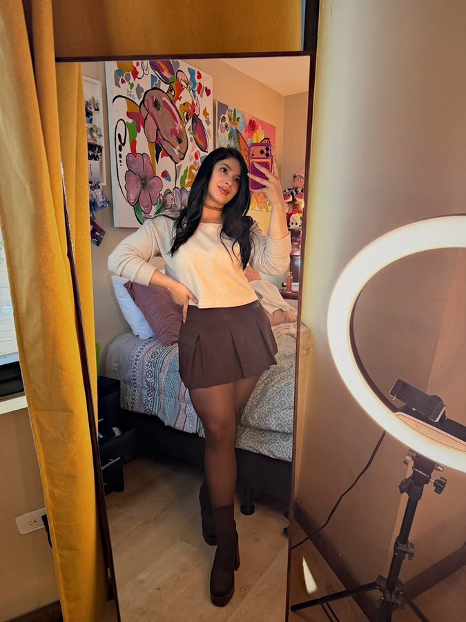 Anita Bikava con falda y botas, foto en espejo